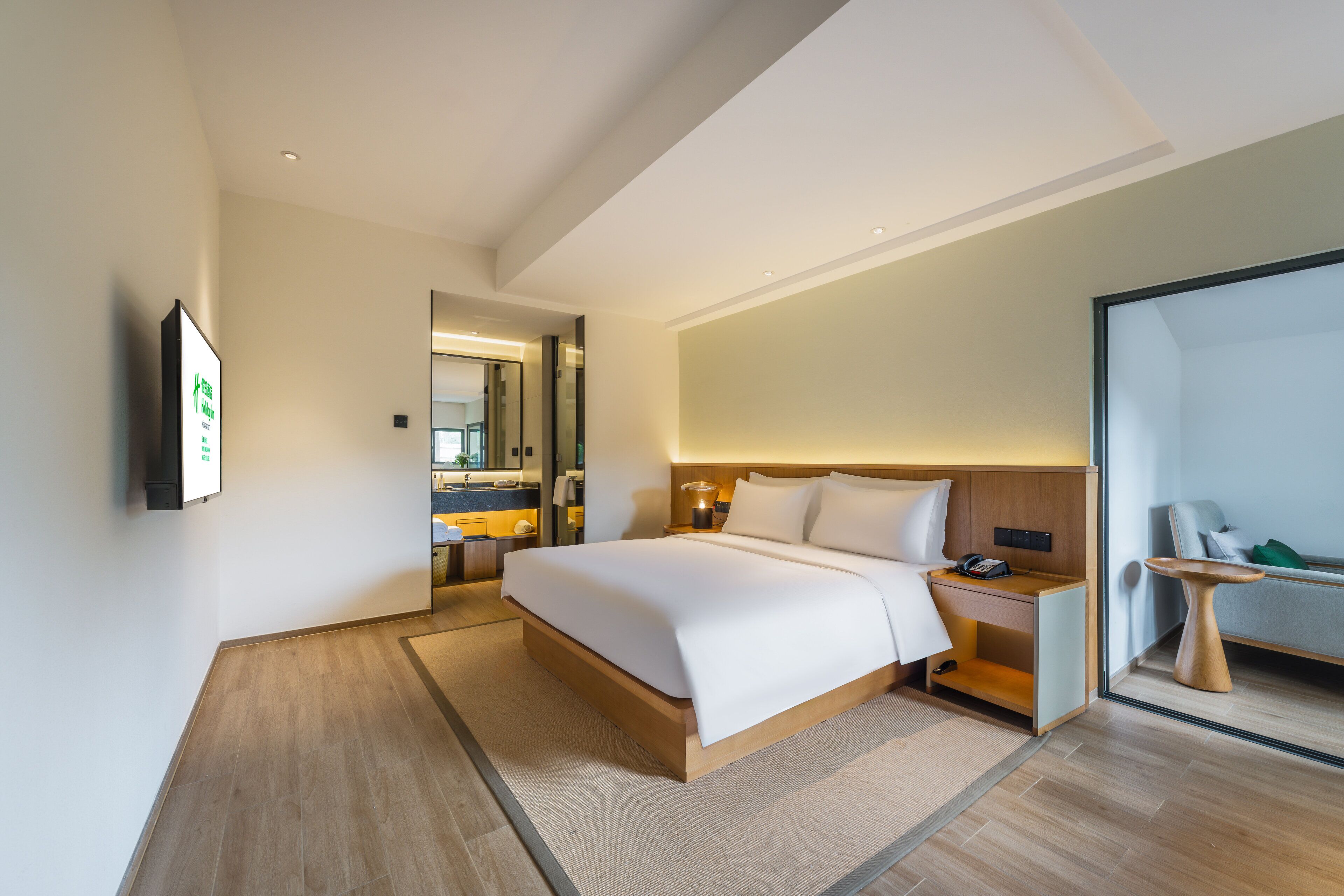 Une chambre d’hôtel moderne avec un grand lit, des tables de chevet, un miroir et une vue sur la ville.
