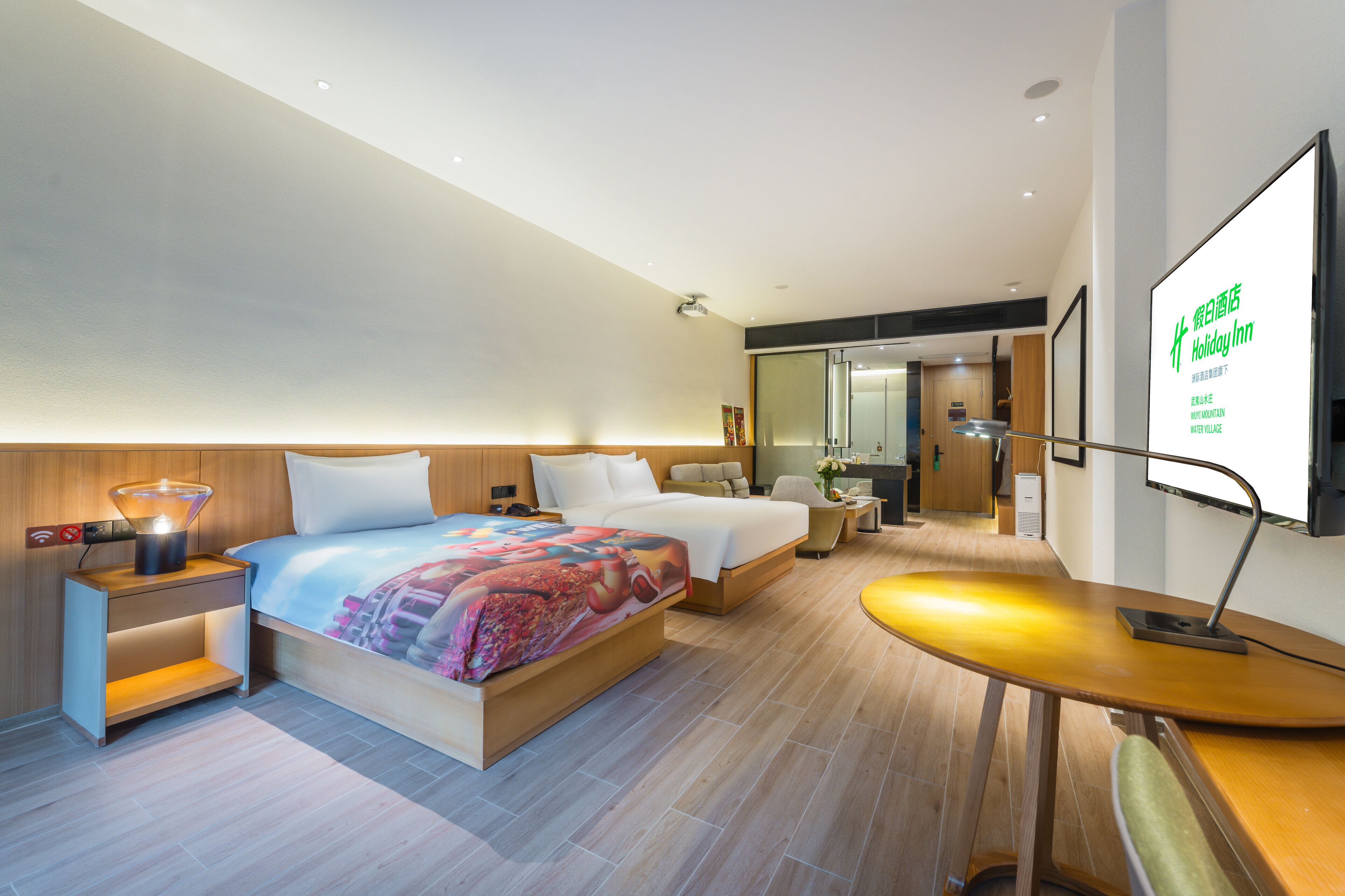 A modern hotel room with a large bed, bedside tables, a desk, and a flat-screen TV.