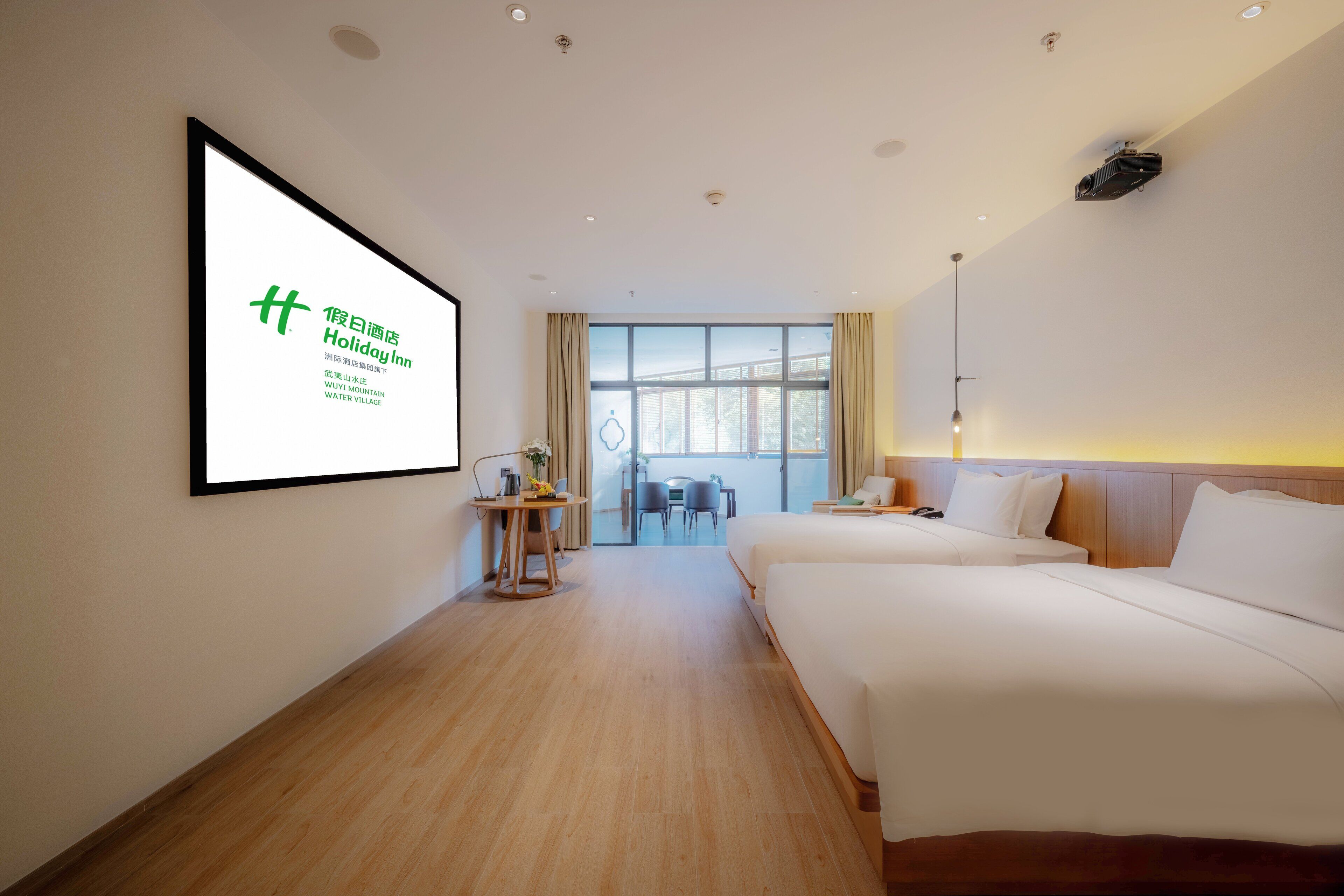 Ett hotellrum med två sängar, ett skrivbord och ett stort fönster.