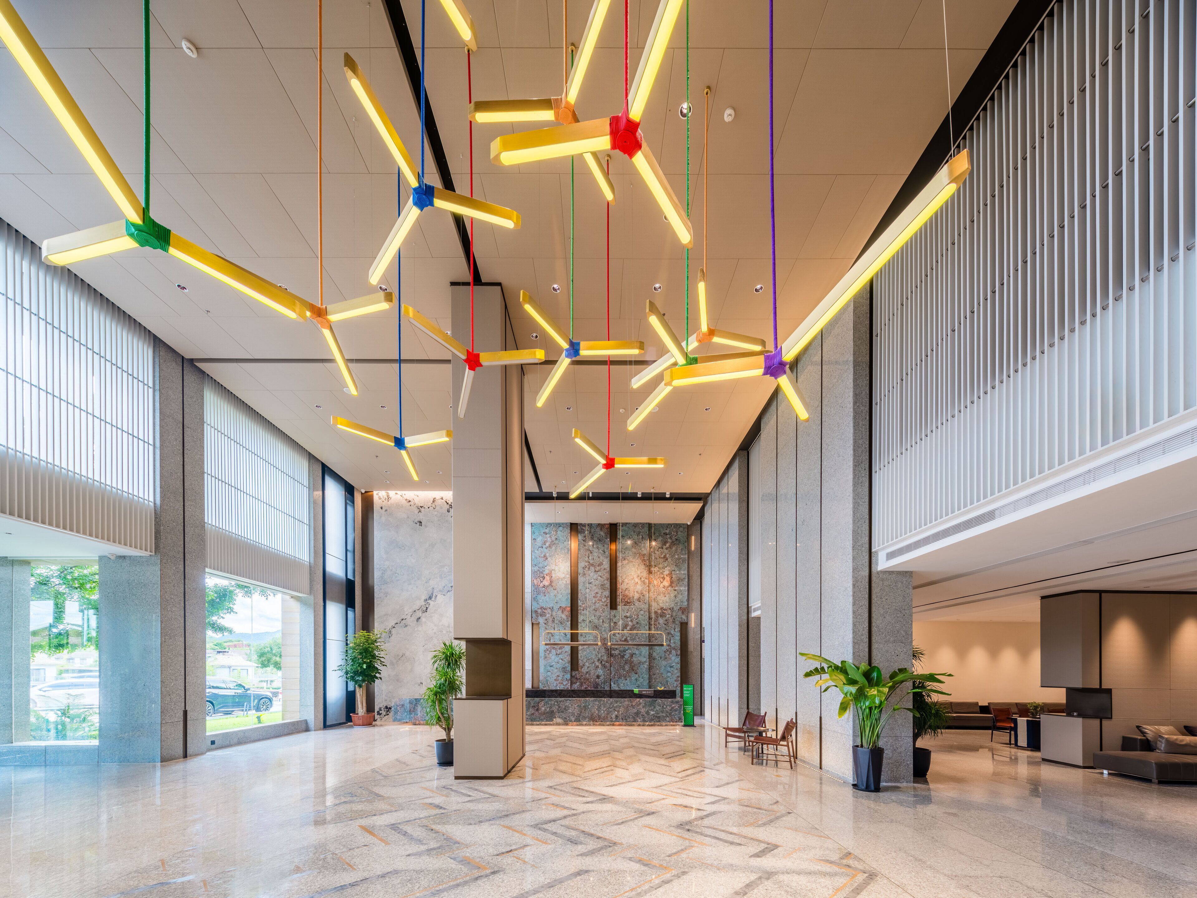 A spacious lobby with a high ceiling, modern lighting fixtures, and a reception desk.