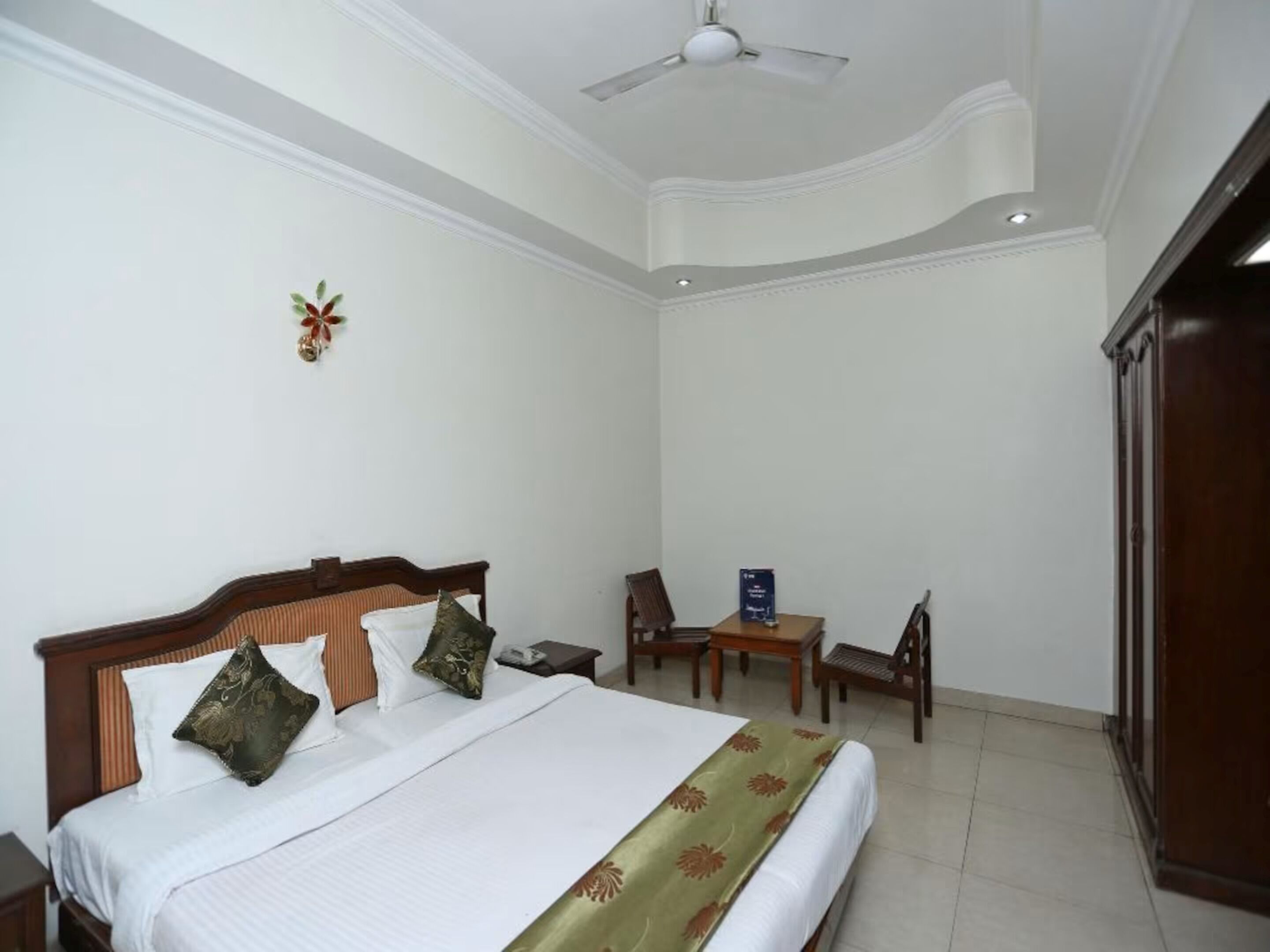 Une chambre d’hôtel avec un grand lit, un ventilateur de plafond, un bureau et une armoire.