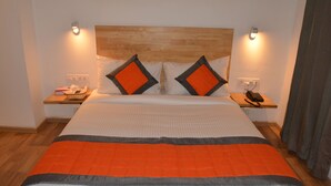 A hotel room with a large bed, two bedside tables, a wooden headboard, and a nightstand with a phone and a basket. - Revking at Hotel Batra  (Ambala)