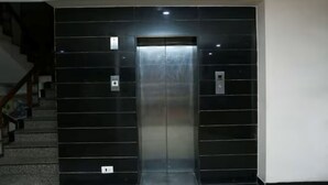A modern elevator with a metallic finish, located in a hallway with a staircase on the left. - Revking at Hotel Batra  (Ambala)