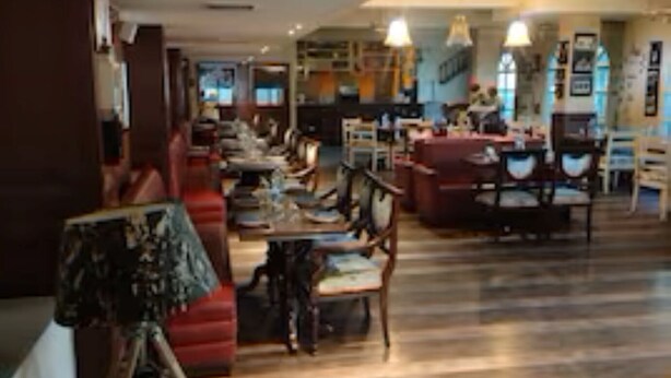 A spacious interior with a wooden floor, red sofas, a dining area, and a staircase leading to an upper level. - Revking at Hotel Batra  (Ambala)