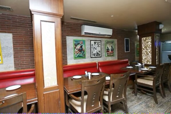 A restaurant with wooden booths, brick walls, and posters on the wall. - Revking at Hotel Batra (Ambala)