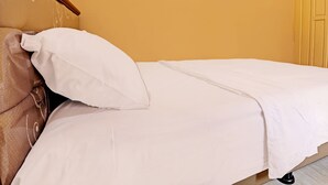 A bed with a white sheet and a beige pillow. - Hotel O Homestay Pasir Padi Permai Syariah (Pangkalpinang)