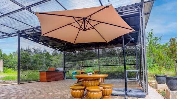 A covered outdoor area with a table and chairs, surrounded by potted plants and a brick floor. - Hotel O Homestay Pasir Padi Permai Syariah (Pangkalpinang)