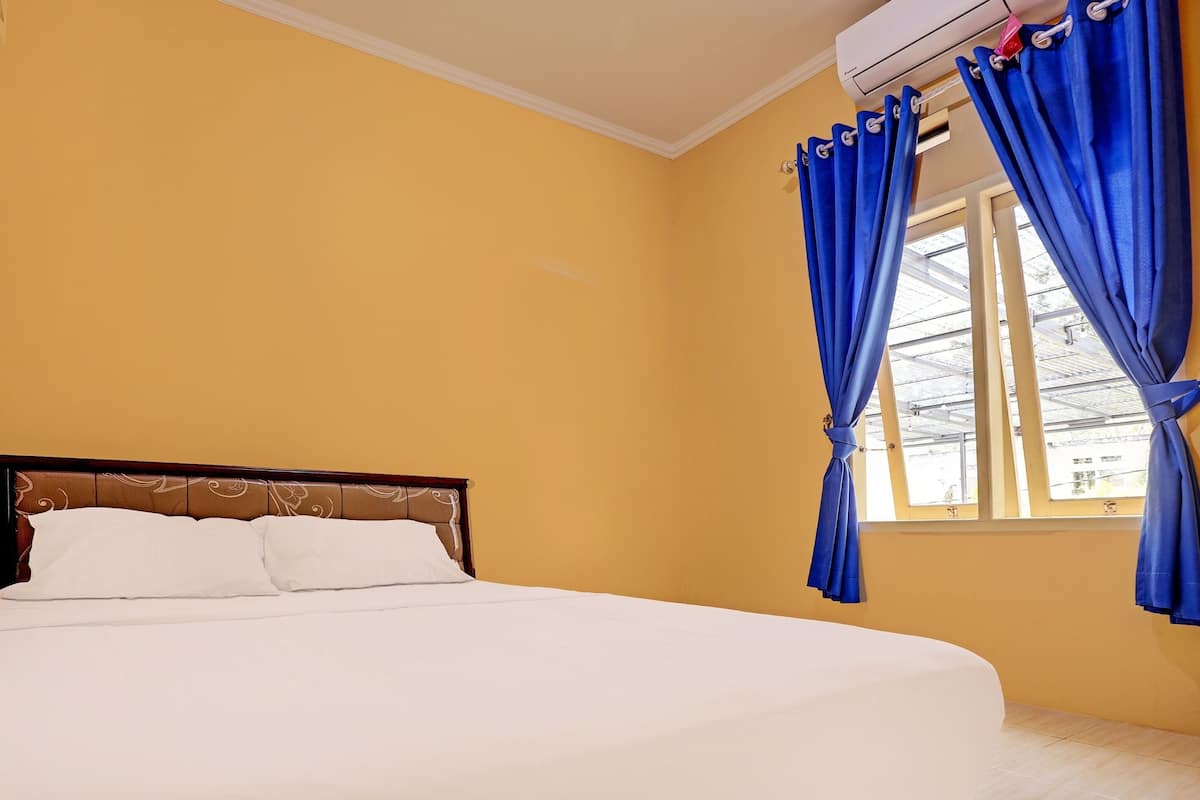 Ein Hotelzimmer mit einem Bett, gelben Wänden und blauen Vorhängen.