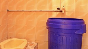A small bathroom with a toilet, a blue trash bin, and a towel rack. - Hotel O Homestay Pasir Padi Permai Syariah (Pangkalpinang)