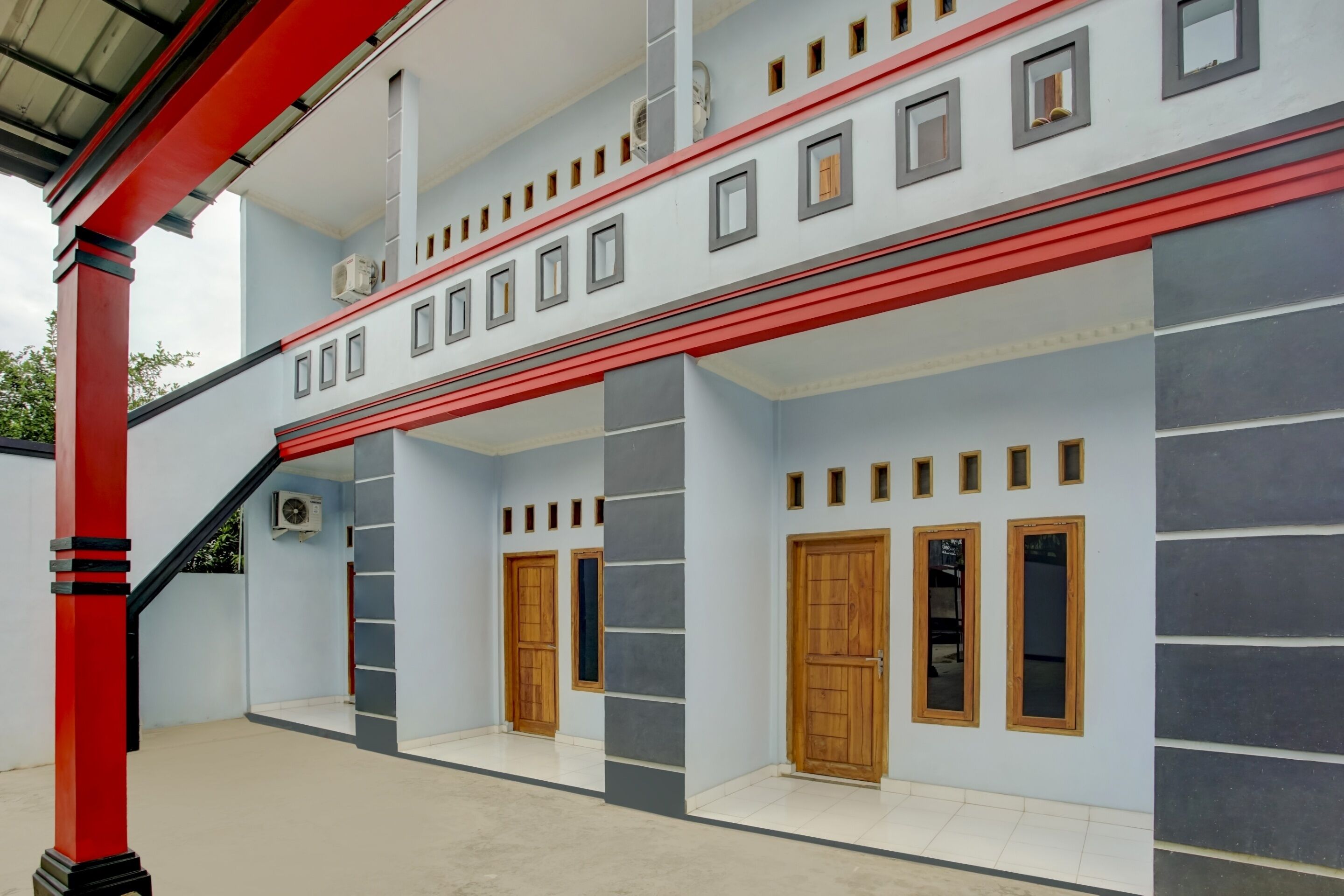 Un edificio de varios pisos con fachada roja y blanca, varias puertas y ventanas.