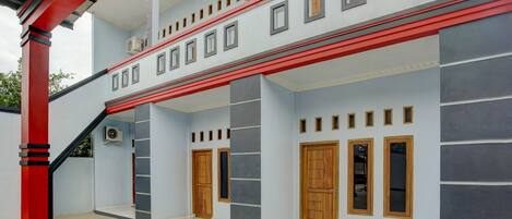 Un edificio de varios pisos con fachada roja y blanca, varias puertas y ventanas.
