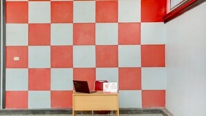 A room with a checkered wall pattern, a desk with a laptop and a box, and a tiled floor. - OYO Life 3982 Azka Homestay Syariah (Bandar Lampung)