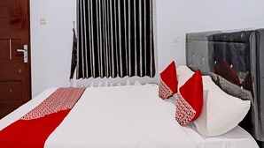Une chambre d’hôtel avec un lit, une porte, une fenêtre avec des rideaux et une prise électrique au mur.