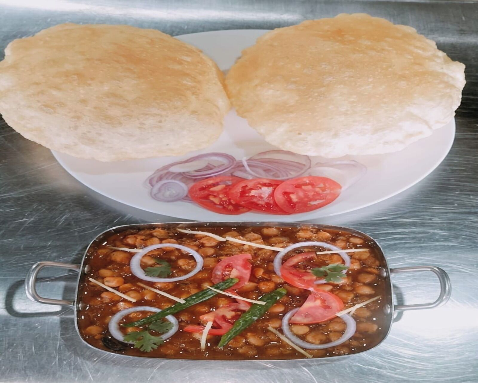 A plate with two bread rolls, sliced onions, and tomatoes.
