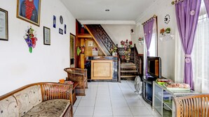 A spacious living area with a sofa, a television, and a staircase leading to an upper floor.