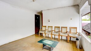 A room with a wooden floor, a green table, and six wooden chairs with cushioned seats.