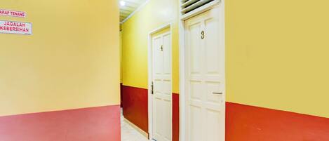 A hallway with yellow and red walls, two white doors, and a vent on the ceiling.