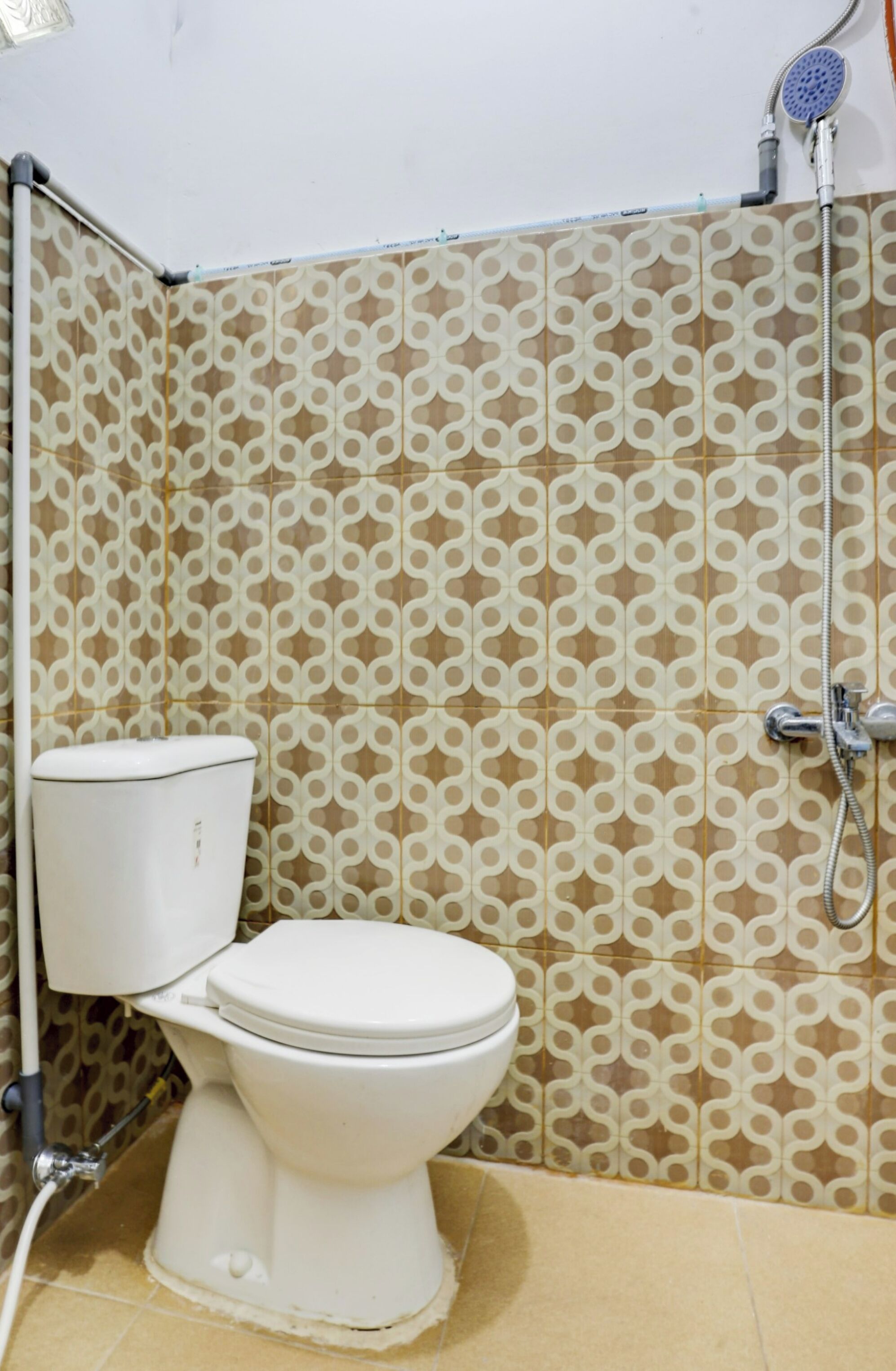 A bathroom with a toilet, a shower, and patterned wall tiles.