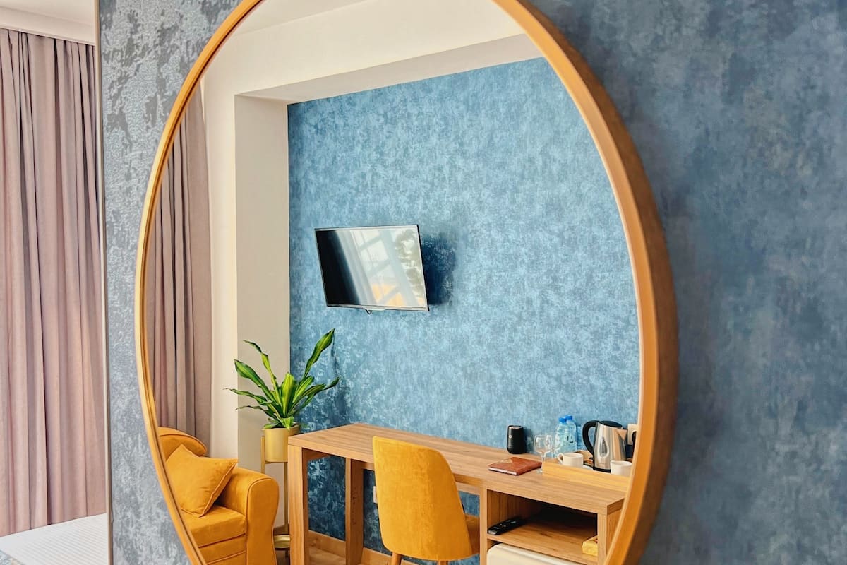 A modern room with a round mirror, a desk, a chair, and a bed.