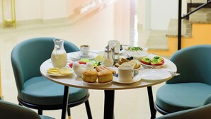 A dining area with a round table set for breakfast, including eggs, toast, and beverages. There are four chairs around the table, and a staircase is visible in the background. - Hotel DownTown Avlabari (Tbilisi)