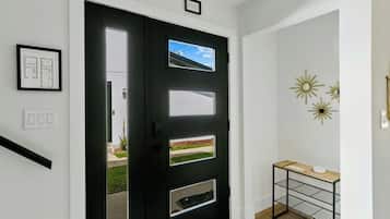 A black door with a window, a small shelf with a vase, and a framed architectural drawing on the wall.
