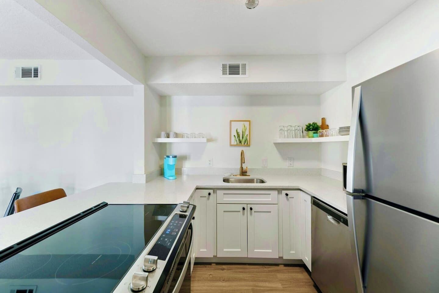 A modern kitchen with white cabinetry, a stainless steel refrigerator, and a built-in oven.