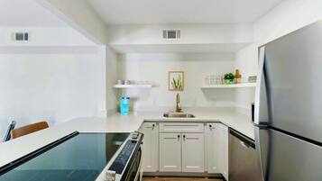 A modern kitchen with white cabinetry, a stainless steel refrigerator, and a built-in oven.