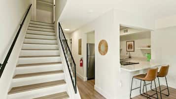 A modern kitchen with a white countertop, two bar stools, and a stainless steel refrigerator.