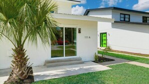 Une maison moderne à deux étages, avec une porte verte, un numéro de maison bien visible et une pelouse bien entretenue.