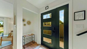 Un vestíbulo moderno con una puerta oscura, una mesita con un espejo y vistas al exterior.