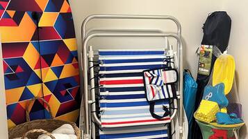 Een kamer met een metalen bedframe, een wand met een kleurrijk geometrisch patroon, een rieten mand met een witte handdoek en een zwarte trekkoordtas.