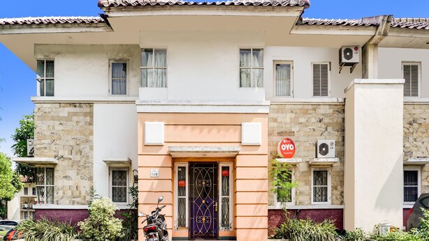 A two-story building with a tiled roof, a central entrance with a decorative door, and a sign indicating a 10-minute walk to the nearest bus stop. - OYO 90204 Surya Inn Syariah (Cikarang)