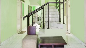A hallway with a staircase, a bench, and a table. - OYO 90204 Surya Inn Syariah (Cikarang)