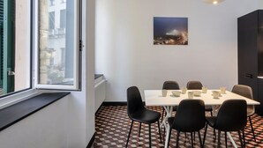 A dining area with a table set for six, six black chairs, a white table, and a patterned floor.