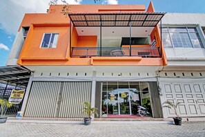 A two-story building with a balcony on the upper floor, large windows, and a garage door. - Hotel O Rosela House Syariah (Pekanbaru)