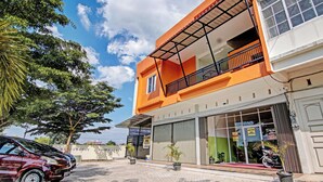 A two-story building with a balcony, large windows, and a parked car. - Hotel O Rosela House Syariah (Pekanbaru)