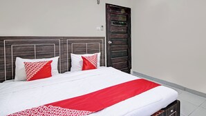 A neatly made bed with white and red bedding, a wooden headboard, and a closed door with a handle. - Hotel O Rosela House Syariah (Pekanbaru)