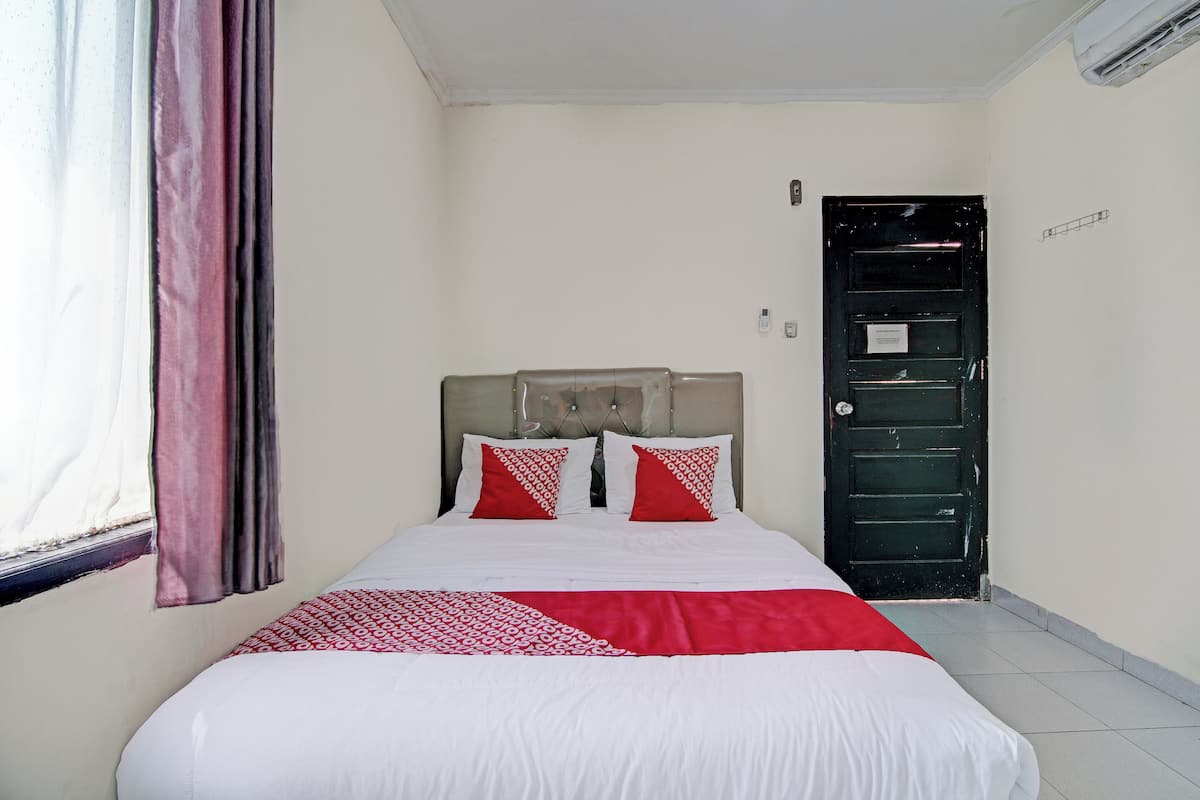 Ein Hotelzimmer mit einem Bett, einem Vorhangfenster, einer Tür und einer wandmontierten Klimaanlage.
