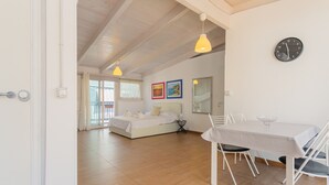 Une chambre spacieuse comprenant un lit, une table à manger avec des chaises et une horloge au mur.