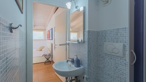 Une salle de bain avec un lavabo blanc, des murs recouverts de carreaux bleus et un miroir au-dessus.