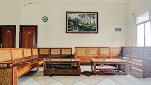Eine Hotelhalle mit einer langen Holzcouch, einem Couchtisch und einem Gemälde, das eine tropische Szene zeigt.