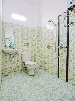 Une salle de bain avec des toilettes, un lavabo et une douche.