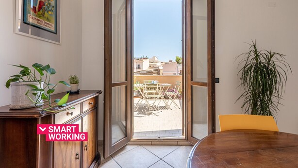 Una stanza con una porta scorrevole in vetro che dà su un patio esterno con tavolo e sedie.