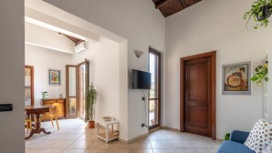 Un'ampia zona giorno con un tavolo da pranzo, un divano blu e una TV a parete.