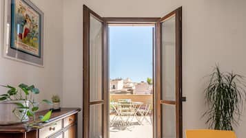 Una stanza con una porta scorrevole in vetro che dà su un patio esterno con tavolo e sedie.
