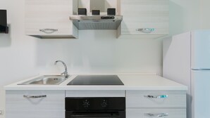 Une cuisine moderne dotée d’un évier en acier inoxydable, d’une cuisinière noire et de meubles blancs.