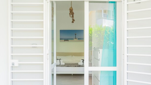 Une chambre à coucher avec un lit, un luminaire suspendu et un tableau représentant une scène de plage.