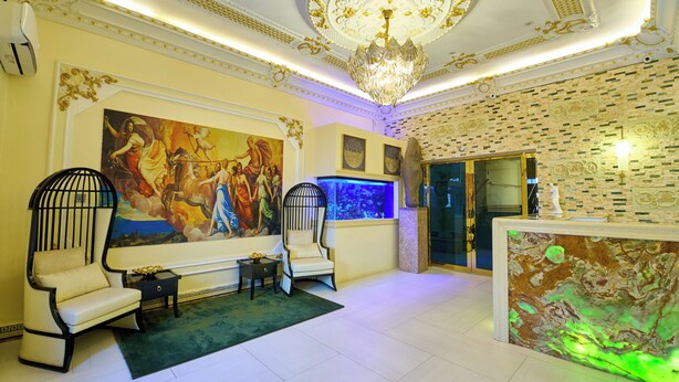 A lobby with a chandelier, a large painting, a reception desk, and a fish tank. - Double D Luxury Apartments (Abuja)