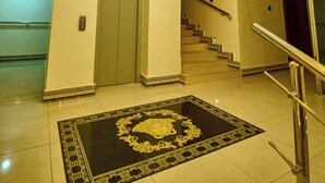 A hotel lobby with a grand chandelier, a marble staircase, and a decorative rug. - Double D Luxury Apartments (Abuja)