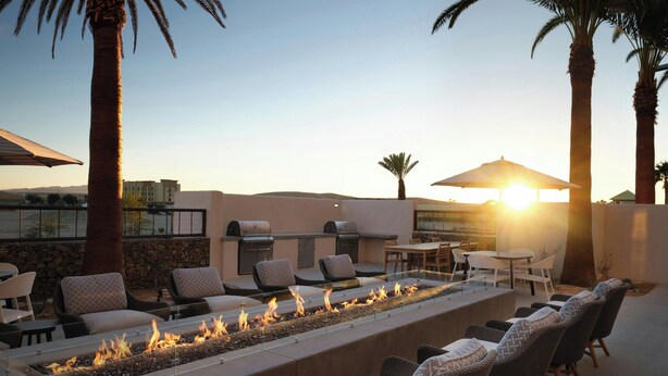 An outdoor patio with a long fire feature, seating, and a grill area.